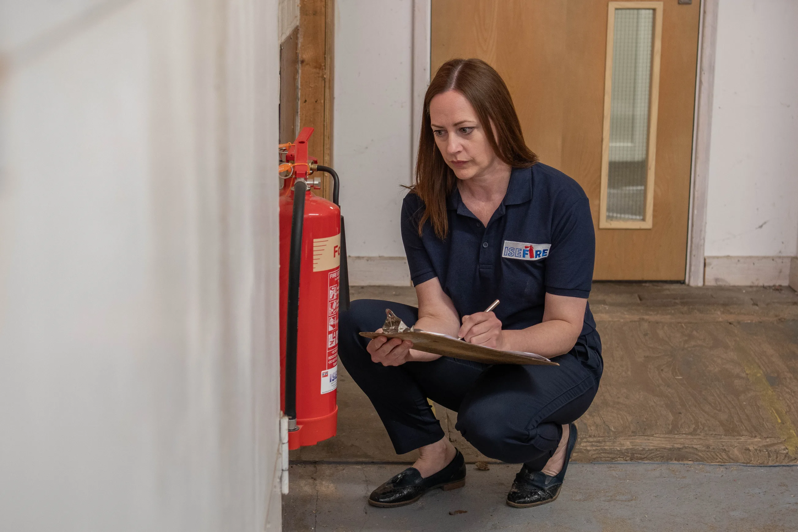 ISE Fire engineer performing an Fire Risk Assessment by inspecting a fire extinguisher.