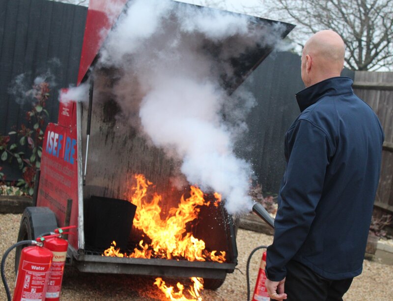 ISE Fire fire safety trainer Harvey Miller providing a live demonstration using a fire extinguisher.
