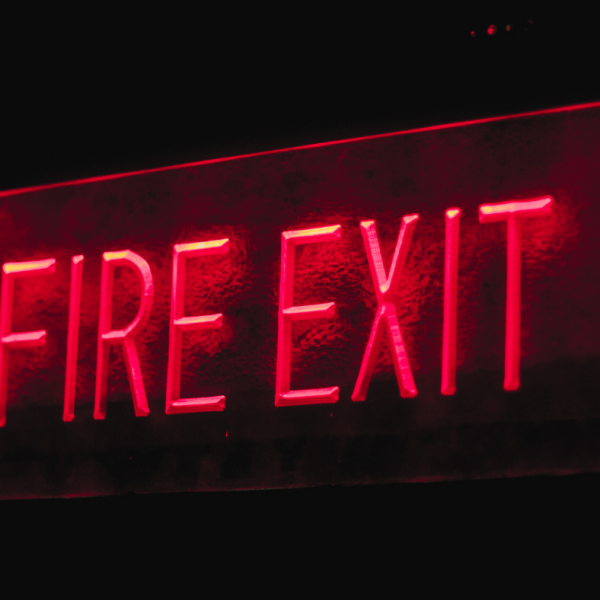 Red fire exit sign with black background colour.